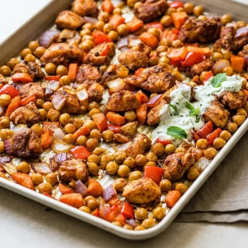 A full sheet pan of Chicken Shawarma Sheet Pan Dinner, with juicy, spice-coated chicken, roasted peppers, onions, carrots, and chickpeas.