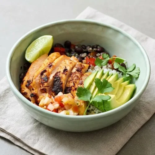 A chicken taco bowl with juicy sliced chicken, seasoned black beans, rice, pico de gallo, and fresh avocado.