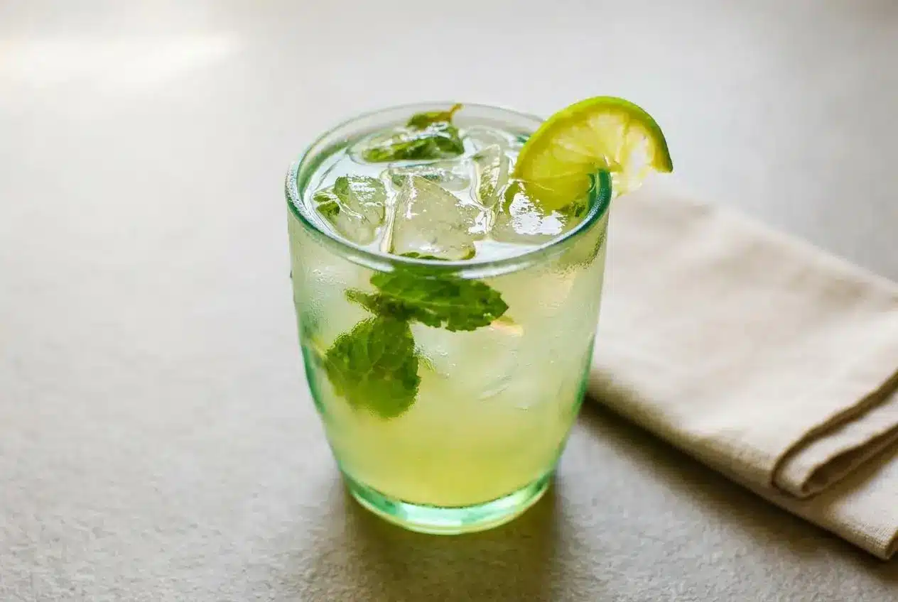 A refreshing coconut water mocktail in a rocks glass with ice, muddled mint leaves, and a fresh lime wedge garnish.