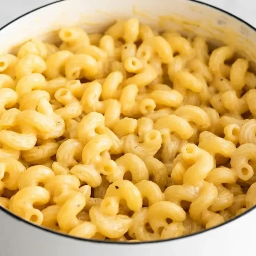 A white bowl filled with cheesy pasta, showing cavatappi noodles coated in a rich, glossy, and creamy three-cheese sauce.