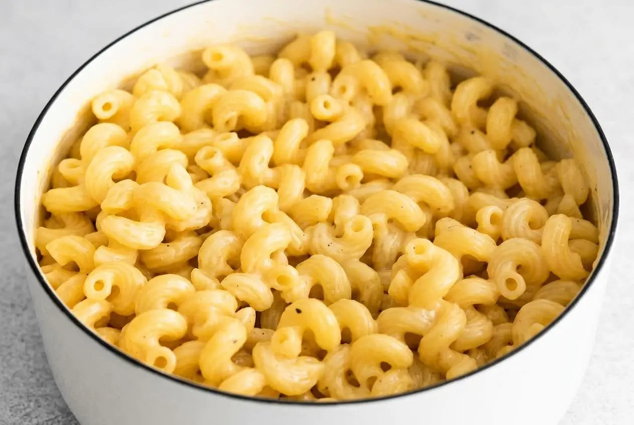 A white bowl filled with cheesy pasta, showing cavatappi noodles coated in a rich, glossy, and creamy three-cheese sauce.
