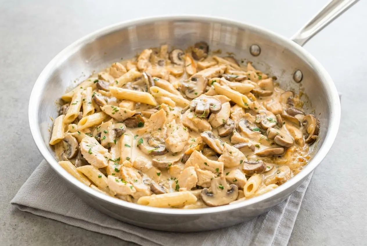 A bowl of Chicken Mushroom Pasta with a glossy cream sauce, tender chicken, sliced mushrooms, and a sprinkle of fresh parsley.