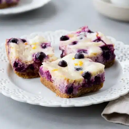 Creamy lemon blueberry cheesecake bars with a golden graham cracker crust and juicy baked blueberries.