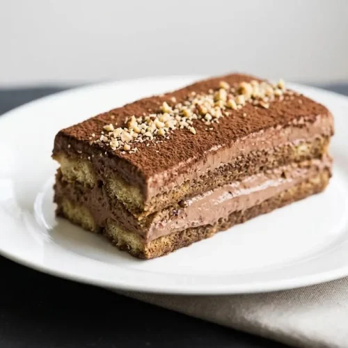 An elegant Nutella Tiramisu layered with coffee-soaked ladyfingers and velvety chocolate hazelnut cream in a loaf pan.