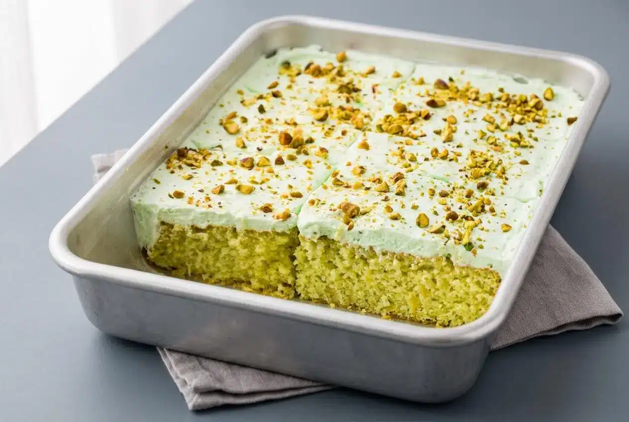 A slice of Pistachio Pineapple Cake showing the moist crumb and fluffy pale green whipped frosting.