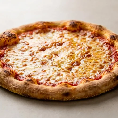 A homemade cheese pizza made with an easy pizza dough recipe, sliced on a pan to show its soft, chewy crust and golden-brown edges.