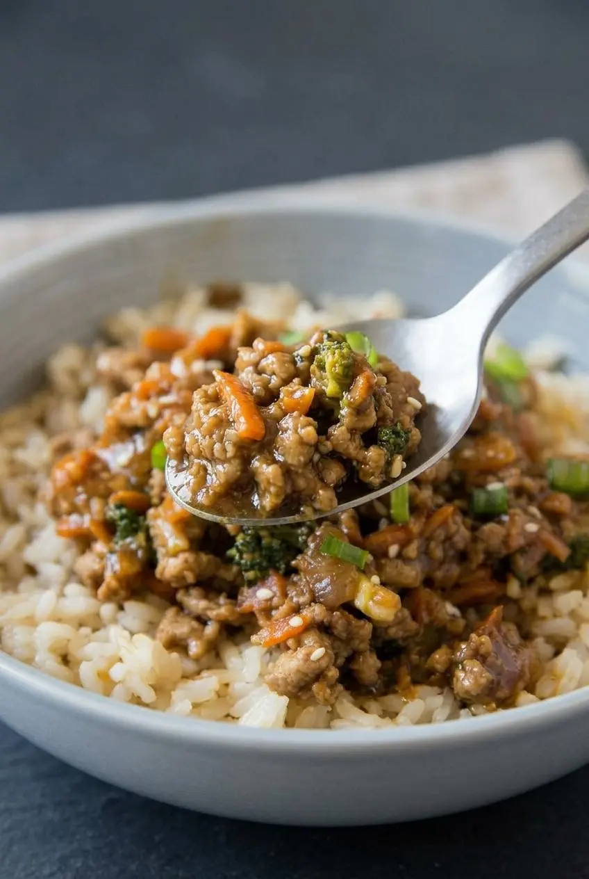 A close-up macro shot on a spoon lifting a bite of ground turkey mixture, showing the glossy sauce, crumbled turkey, and bits of green