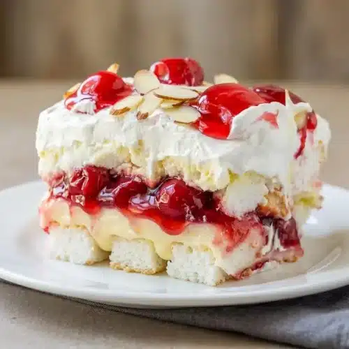 Heaven On Earth Cake slice showing layers of angel food cake, creamy pudding, whipped topping, and cherry filling.
