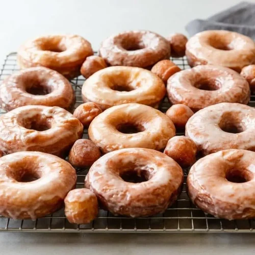 A stack of homemade Glazed Doughnuts from a recipe, showing their shiny, set vanilla glaze and soft, pillowy shape.