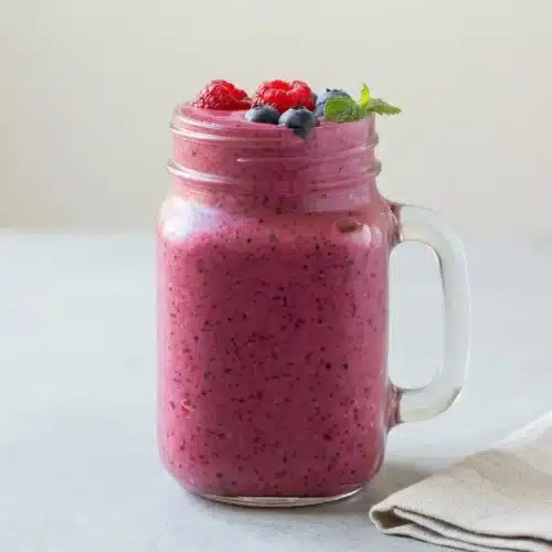 A thick and creamy mixed berry smoothie in a tall glass, ready to drink.
