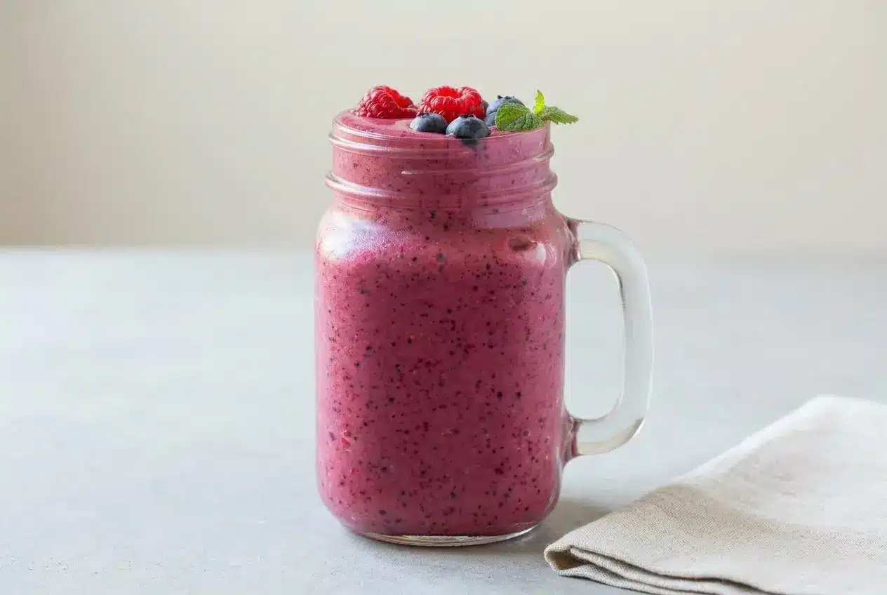 A thick and creamy mixed berry smoothie in a tall glass, ready to drink.