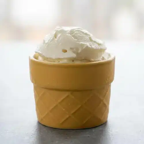 Two scoops of rich, creamy Ninja Creami Vanilla Ice Cream in a white bowl, showing a perfectly smooth texture with vanilla bean specks.