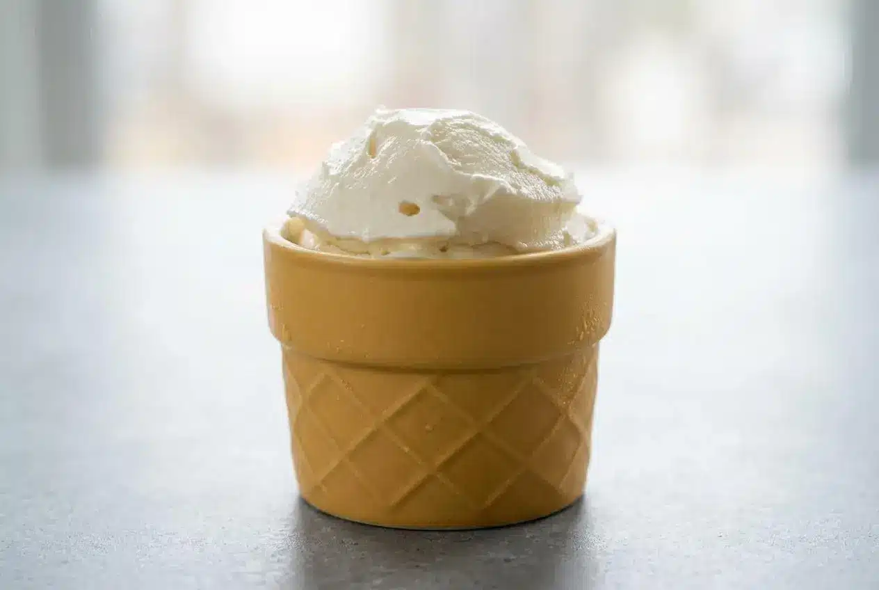 Two scoops of rich, creamy Ninja Creami Vanilla Ice Cream in a white bowl, showing a perfectly smooth texture with vanilla bean specks.