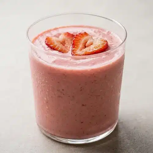 A Roasted Strawberry Protein Smoothie served in a tall glass, showing its thick, creamy texture and rich pink color.