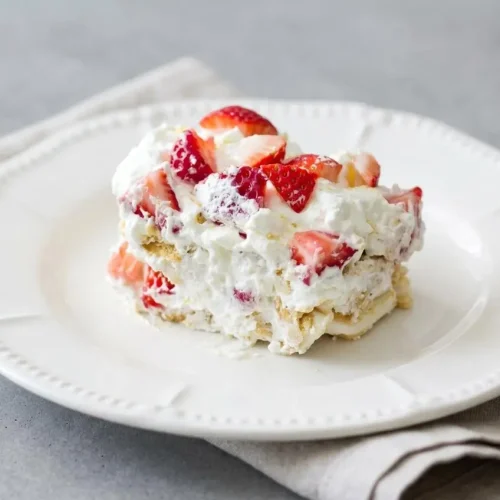 A layered Strawberry Lemonade Icebox Cake topped with fluffy lemon whipped cream and fresh sliced strawberries.