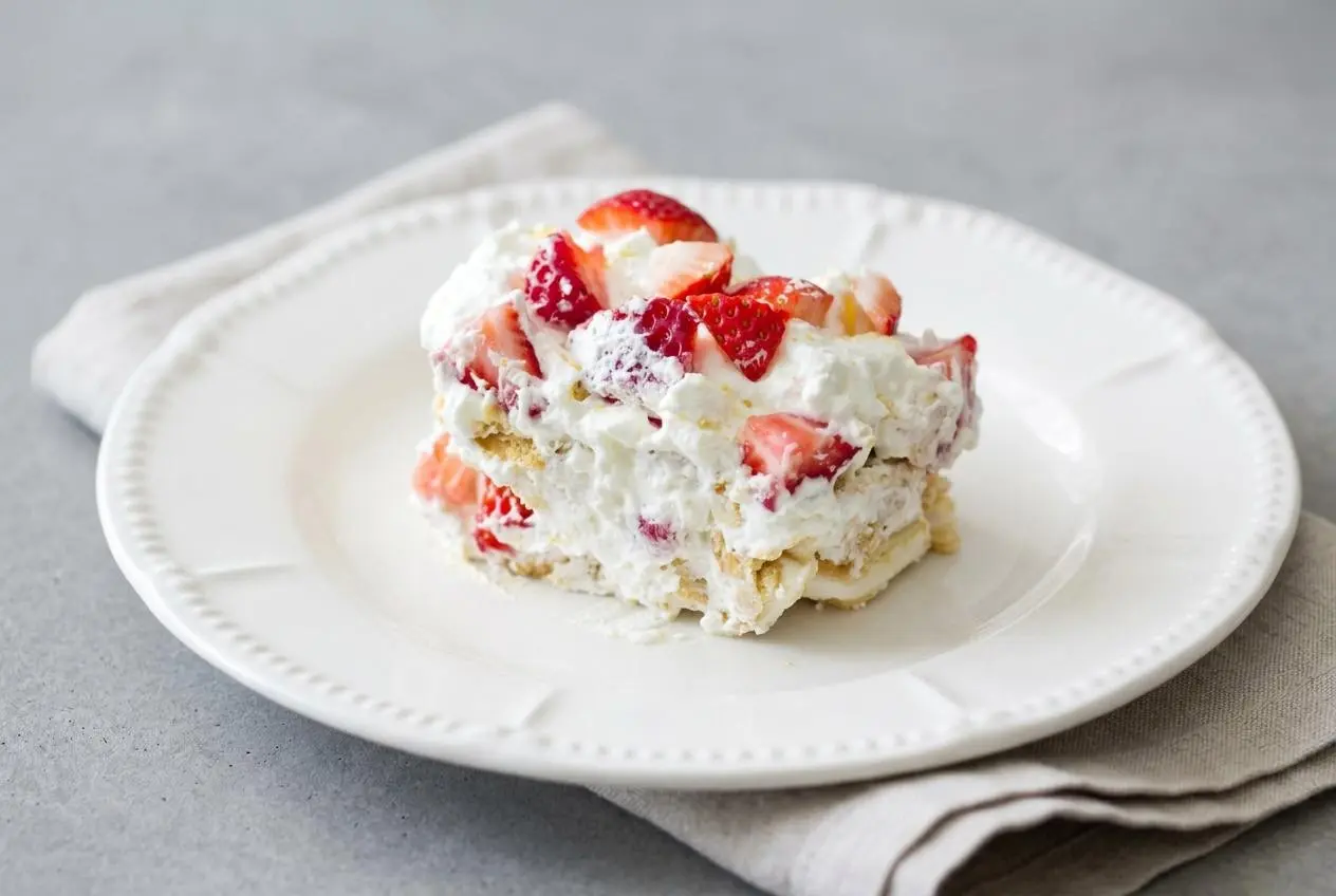 A layered Strawberry Lemonade Icebox Cake topped with fluffy lemon whipped cream and fresh sliced strawberries.