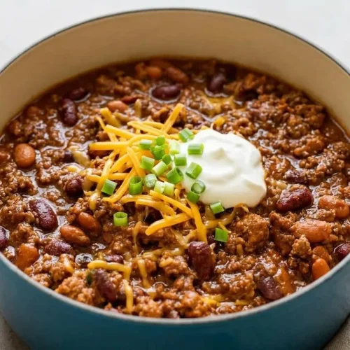 A white bowl filled with The Pioneer Woman Chili, showing its thick, beefy texture and dark red, glossy sauce, ready to be served.