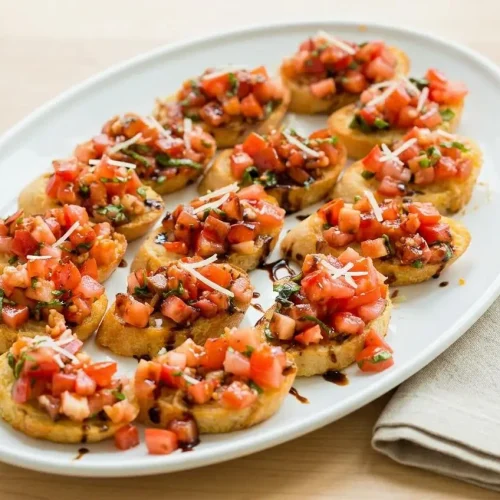 A platter of classic tomato bruschetta, with juicy diced tomatoes and fresh basil piled on crisp, golden garlic toasts.
