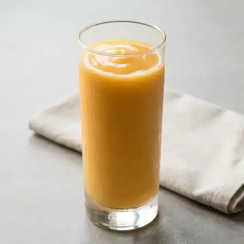 A tall glass of creamy Tropical Papaya Batido Fruit Shake, showing its smooth, vibrant orange texture.