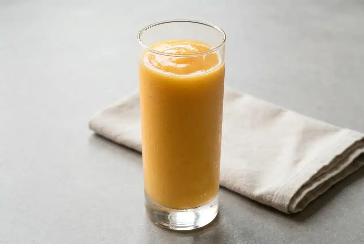 A tall glass of creamy Tropical Papaya Batido Fruit Shake, showing its smooth, vibrant orange texture.