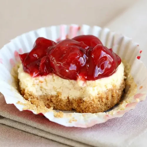 Cherry cheesecake cupcake with a crisp graham crust, smooth cream cheese filling, and glossy cherry topping.