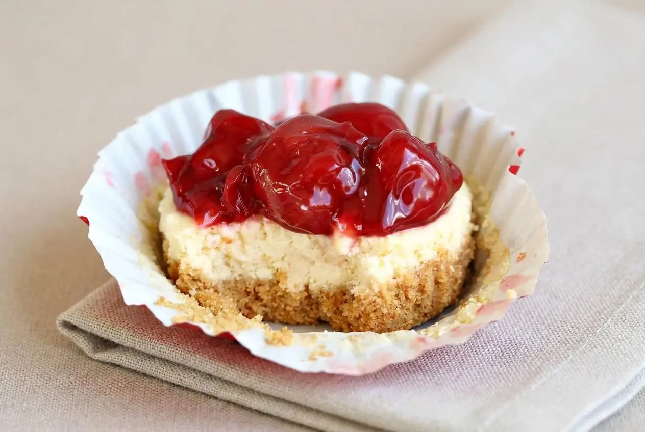 Cherry cheesecake cupcake with a crisp graham crust, smooth cream cheese filling, and glossy cherry topping.
