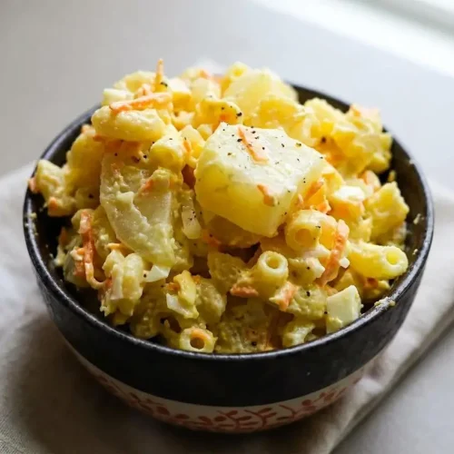 Creamy potato mac salad with soft macaroni, tender potato cubes, and grated carrots in a glossy mayonnaise dressing.