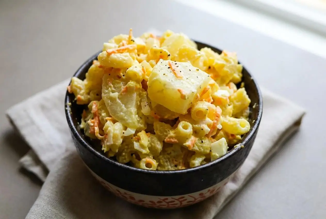 Creamy potato mac salad with soft macaroni, tender potato cubes, and grated carrots in a glossy mayonnaise dressing.