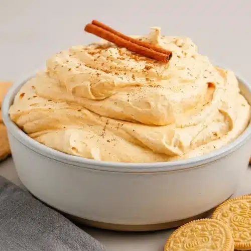 Creamy pumpkin cheesecake dip served in a bowl, showcasing a thick, fluffy, spiced orange texture.