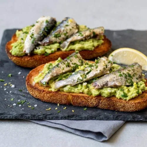 Crisp sardine toast topped with thick mashed avocado, marinated brisling sardines, fresh parsley, and lemon zest.