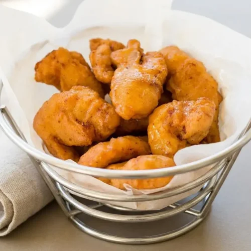 Crispy golden Chinese chicken fingers served on a platter with sweet and sour dipping sauce.