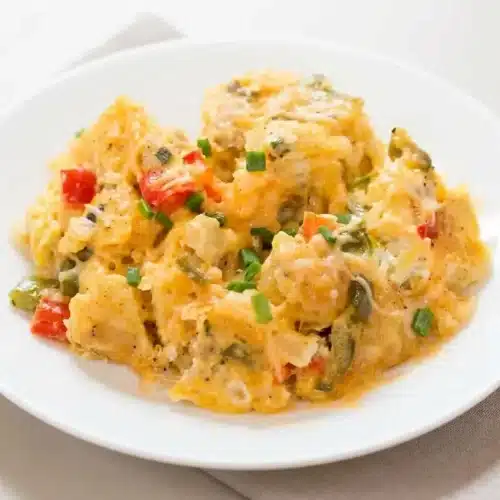 Crock Pot egg scramble with fluffy eggs, golden melted cheese, and tender potatoes topped with fresh chives.
