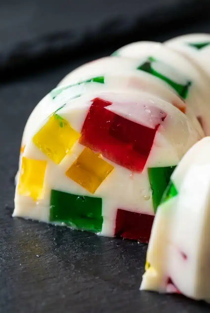 Macro view of a sliced Gelatina De Mosaico edge showing sharp gelatin cubes with zero color bleeding.