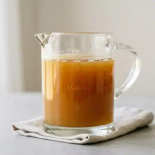 Warm and glossy golden buttermilk syrup cascading beautifully in a smooth, thick ribbon from a glass pitcher.