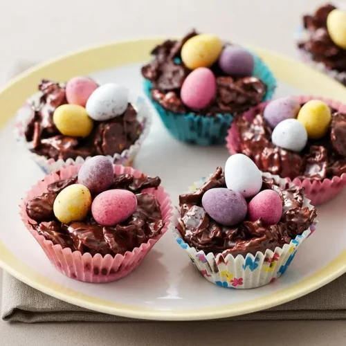 A finished Chocolate Easter egg nest cake made of crispy cornflakes coated in glossy melted chocolate and topped with three mini chocolate
