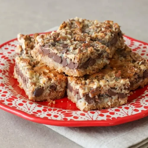 Sliced hello dolly bars with golden toasted coconut, melted chocolate chips, and a buttery graham crust.