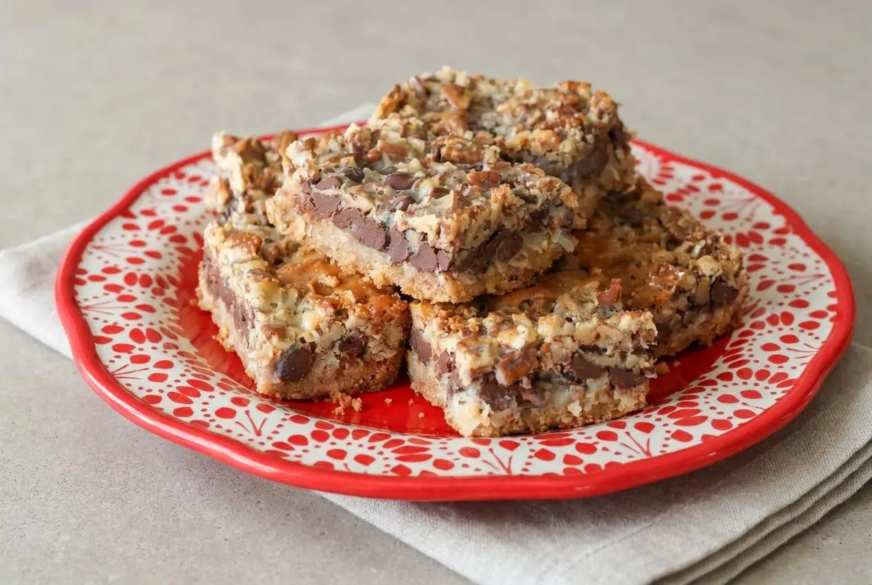 Sliced hello dolly bars with golden toasted coconut, melted chocolate chips, and a buttery graham crust.