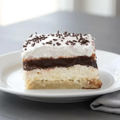 Slices of chilled Layered Chocolate Pudding Dessert showing cream cheese, chocolate pudding, and whipped topping layers.
