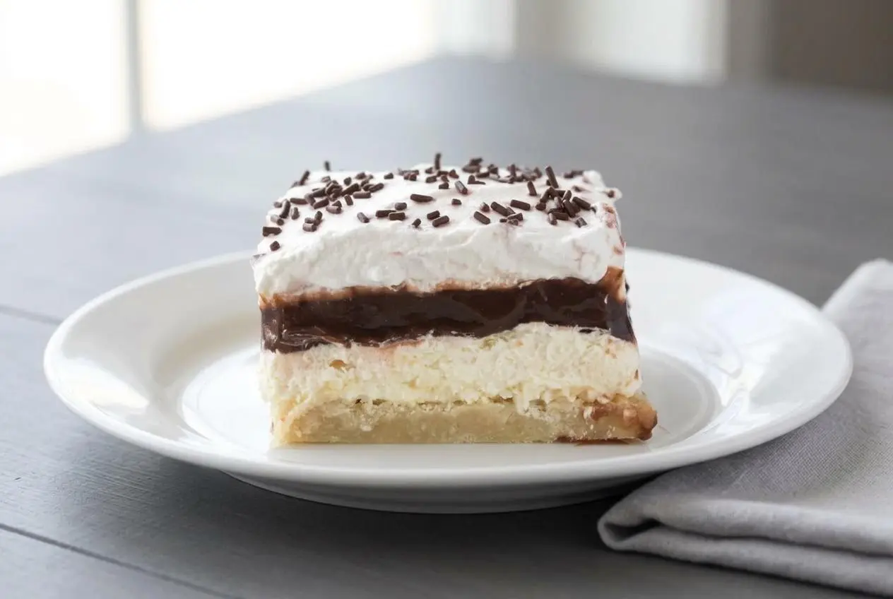 Slices of chilled Layered Chocolate Pudding Dessert showing cream cheese, chocolate pudding, and whipped topping layers.