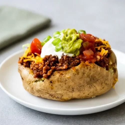 Taco potatoes baked with crisp skins and loaded with seasoned ground beef, melted cheddar cheese, and fresh toppings.