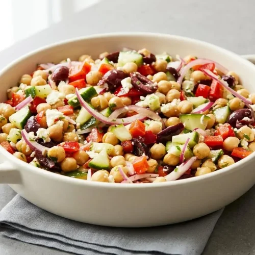 Mediterranean chickpea salad in a bowl with crisp cucumbers, chunky feta, and Kalamata olives coated in a cloudy vinaigrette.