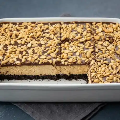 Slices of no bake buckeye cheesecake bars showing chocolate cookie crust, peanut butter filling, and chocolate ganache.