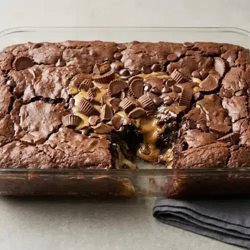 Baked Reese’s Peanut Butter Earthquake Cake showing a rich chocolate surface with gooey cream cheese swirls and melted peanut butter cups.