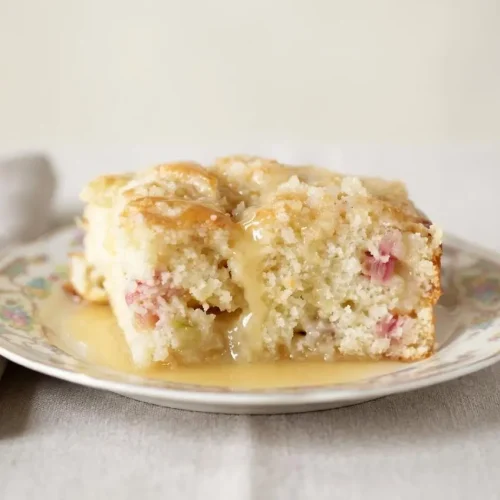 Rhubarb Streusel Cake with Warm Vanilla Sauce featuring a crackly sugar topping and a glossy drizzle