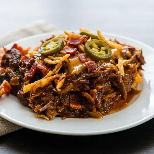 Tender shredded Slow Cooker Cowboy Beef glazes in a sweet and smoky barbecue sauce with bacon and jalapeños.