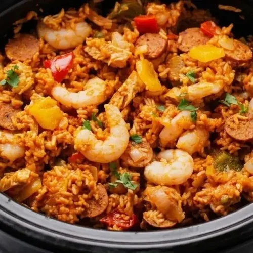 Slow cooker jambalaya featuring distinct white rice, smoky andouille sausage, and tender pink shrimp in a hearty tomato base.
