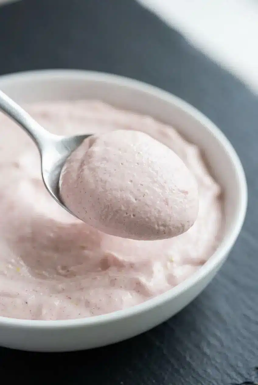 Close up of smooth, airy strawberry dip resting on a silver spoon.