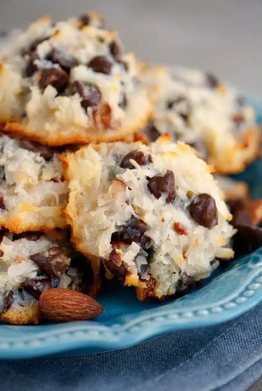 Macro shot of a baked coconut cookie showing toasted golden-brown edges, melted chocolate, and a crunchy almond.