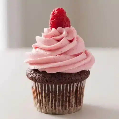 Silky smooth, vibrant pink raspberry buttercream frosting with soft peaks on a swirling spread.