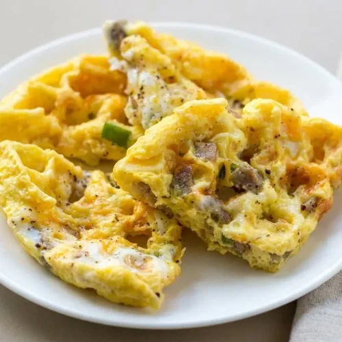 Golden crisp waffle iron omelette square with melted cheddar and diced sausage.